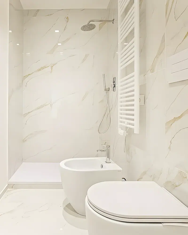 Baño en porcelánico efecto mármol blanco con plato de ducha y sanitarios suspendidos