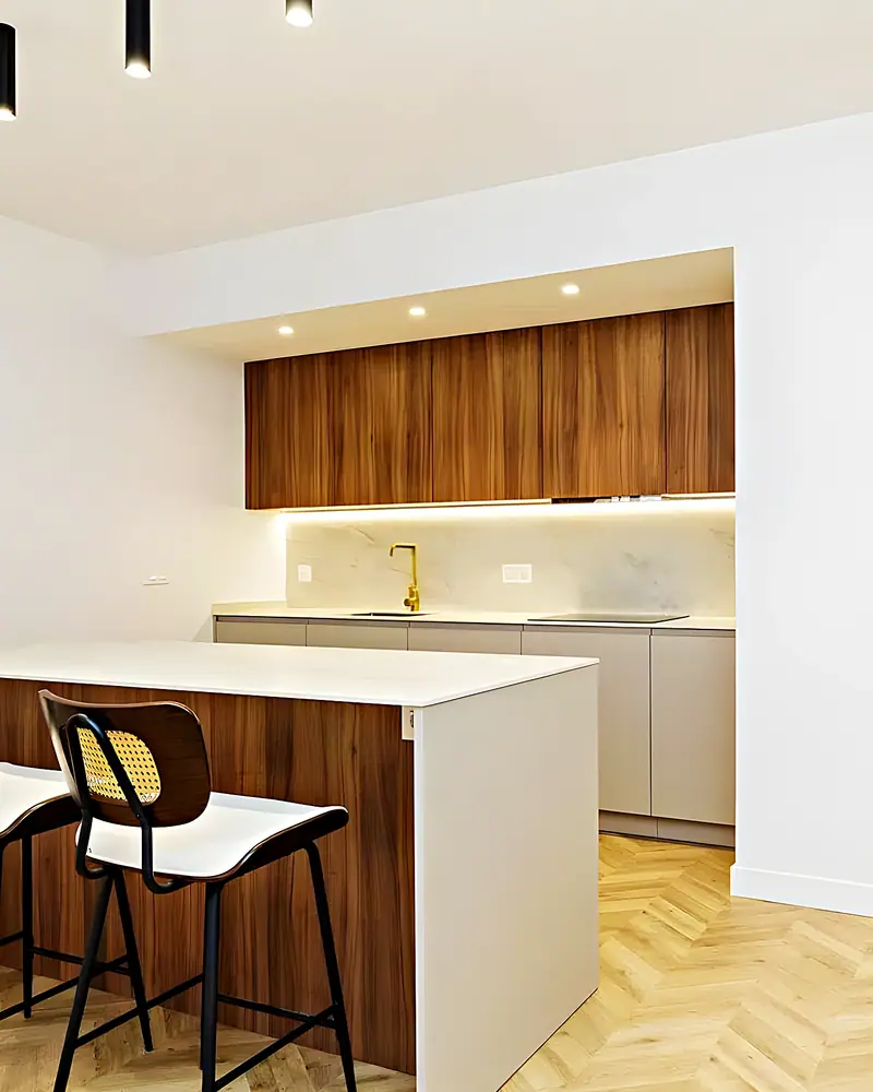 Cocina abierta con isla y taburetes junto al pasillo de un piso reformado