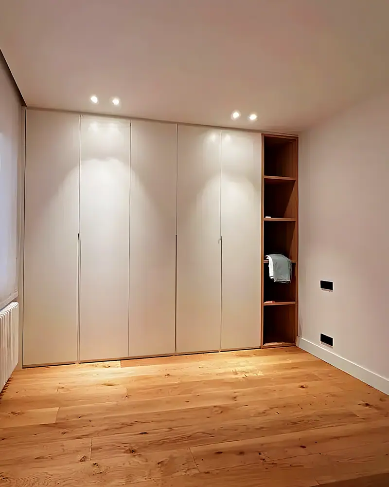 Dormitorio con armarios empotrados hasta el techo, estantería de madera y suelo de roble