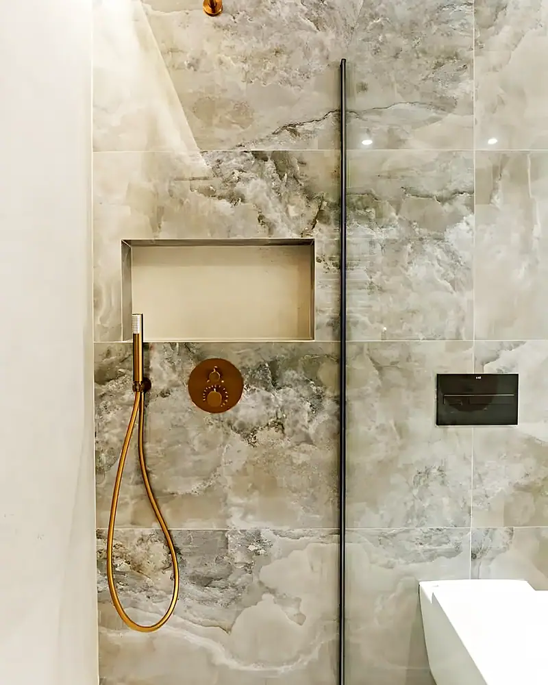 Ducha de obra revestida en ónix con rociador y grifería en oro cepillado y hornacina